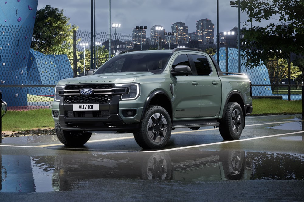 Ford Ranger hybride rechargeable gris stationné devant un paysage urbain au crépuscule.