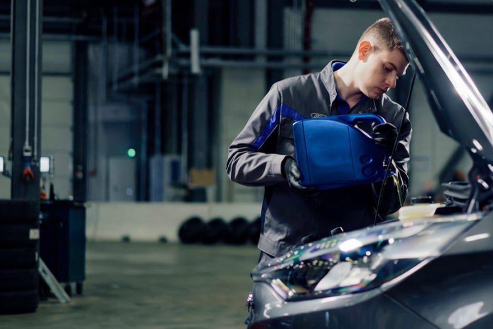 Vue de côté d'un technicien agréé Ford effectuant des réparations sur un véhicule dans un garage.