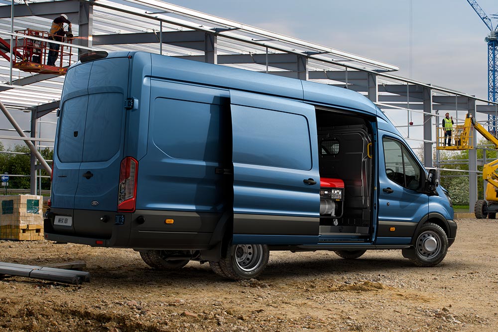 Camionnette Ford Pro Transit bleue garée sur un chantier de construction.