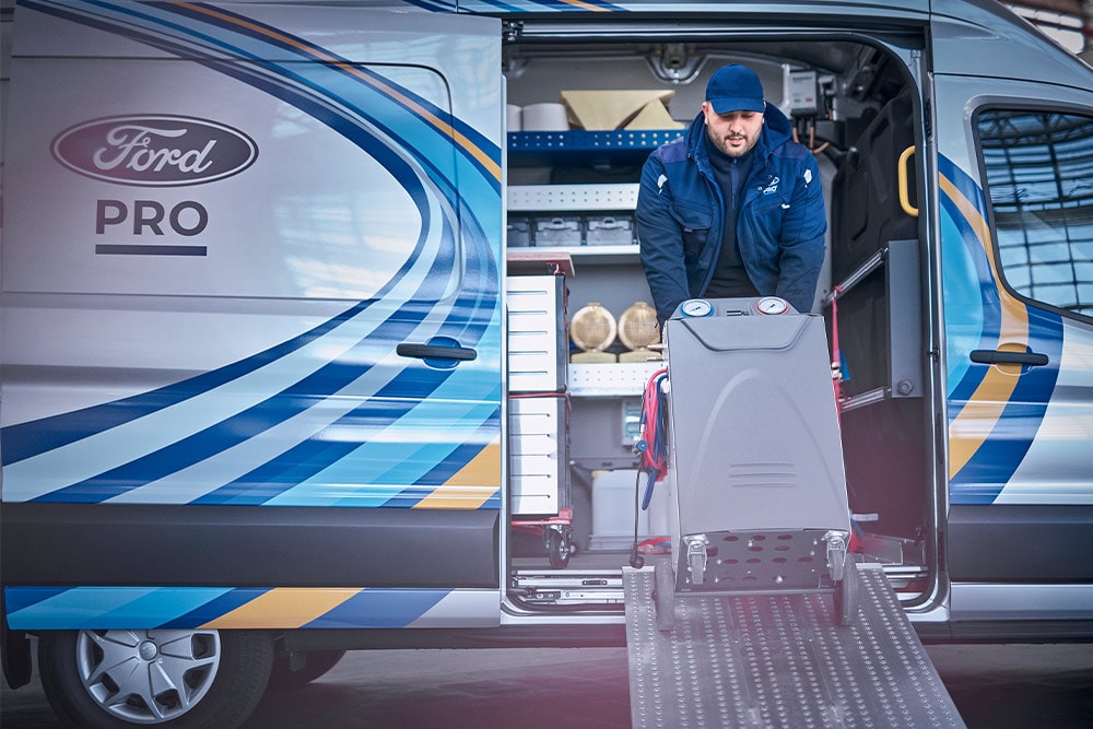 Un technicien décharge du matériel par une rampe depuis une camionnette Ford Mobile Service.