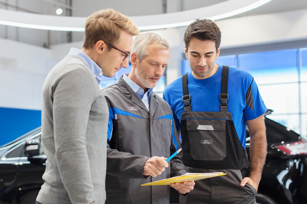 Trois experts discutent des options de véhicules prêts à l'emploi dans un Ford Transit Centre.