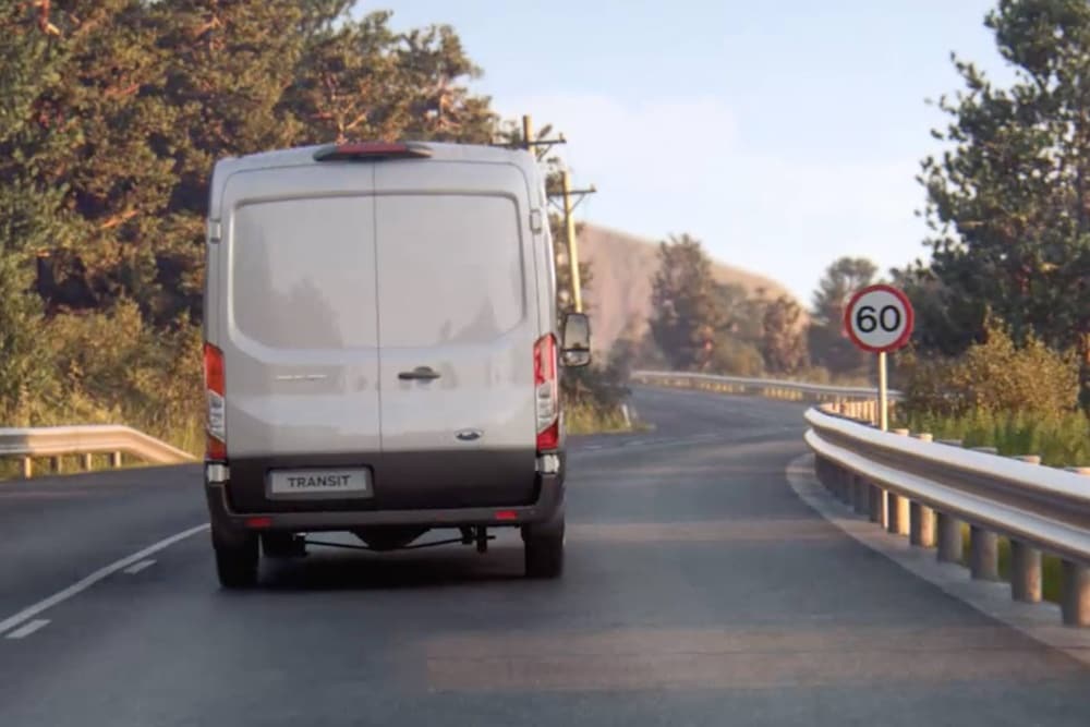 Fourgonnette Ford Transit roulant sur la route, panneau de signalisation vu de l'arrière